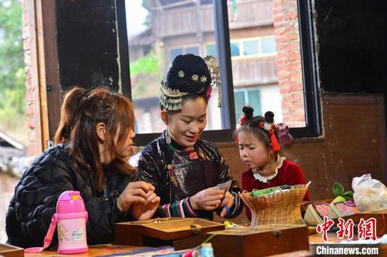 春节期间，游客在贵州省从江县高增乡非遗传承基地体验侗族刺绣。卢忠南 摄