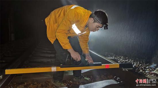 玉林工务段职工正在使用道尺检测线路高低、方向、水平等几何尺寸和线路钢轨平顺度。李慕传  摄.
