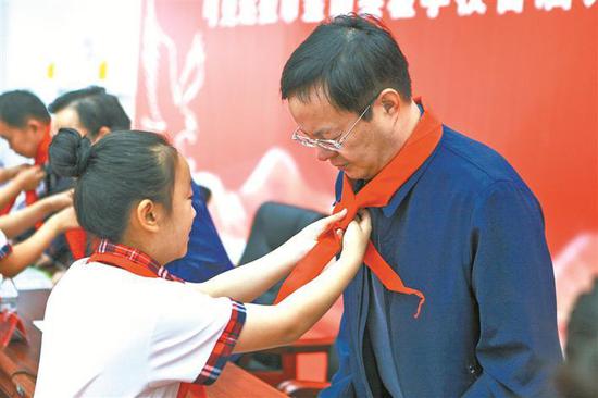 2019年9月6日，可克达拉市金山实验学校开学，小朋友为丁憬（右一）系红领巾。杨俊钦 摄