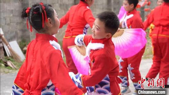 苏瑞翔、苏佳成两兄弟和女同学一手扬帕、一手舞扇，为农户“跳花灯”送祝福。谢小龙 摄