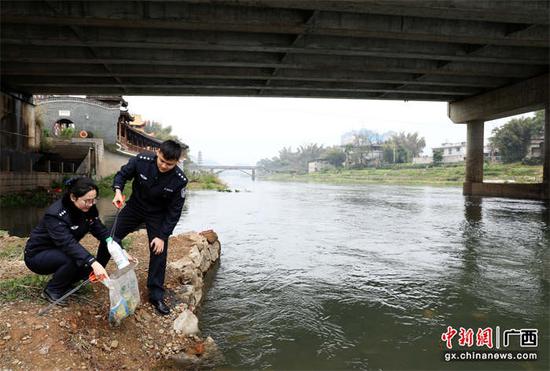 图为志愿者在清理河堤两岸生活垃圾。甘勇 摄