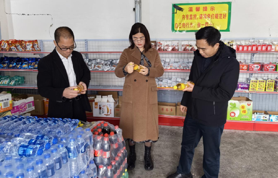 南丹县检察院党组书记、检察长刘晓波（右一）现场查看食品情况。李晓雷 摄