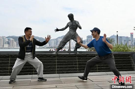 2023年11月，香港，游客摆出李小龙铜像的姿势合影。李志华 摄