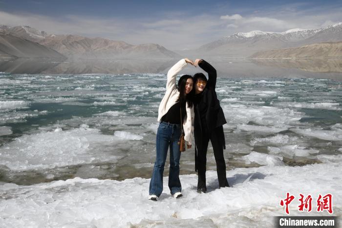图为两名游客在帕米尔高原上的白沙湖畔拍照。中新网记者 孙亭文 摄