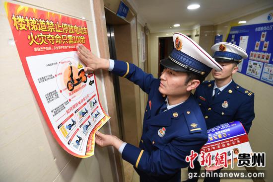 4月11日，贵阳市南明区消防救援大队的消防员正在花果园大街C区楼道内张贴电动自行车火灾防控宣传海报。