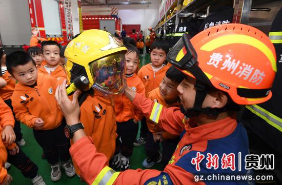 4月11日，在贵阳市南明区消防救援大队后冲路消防救援站，小朋友们正在消防员的帮助下试戴消防头盔。