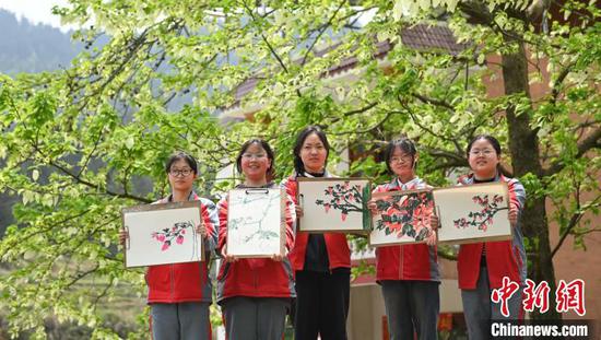 4月10日，学生在贵州省铜仁市松桃苗族自治县乌罗镇毛溪村的鸽子花树下画画。谢慧芳 摄