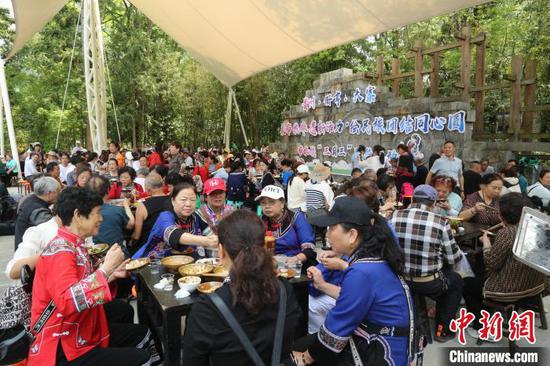 图为贵州册亨大寨村布依群众欢庆传统节日“三月三”，村民与游客吃长桌宴。叶方杰 摄