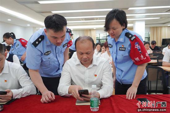 活动现场，民警指导员工们下载安装“国家反诈中心”APP。杨芳 韦莹  摄影报道