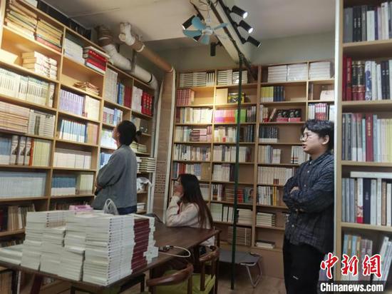 图为杨不正（右）在自己的书店与书友聊天。周燕玲 摄