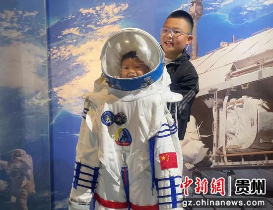 图为在贵州省科学技术馆游览的小朋友体验太空服。王秋旭摄
