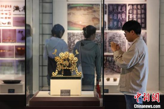 5月17日,参观者在拍摄播州杨氏土司考古成果展展出的明代金镶宝三龙五凤冠(复制)。中新网记者 瞿宏伦 摄 5月17日,参观者在拍摄播州杨氏土司考古成果展展出的明代金镶宝三龙五凤冠(复制)。中新网记者 瞿宏伦 摄
