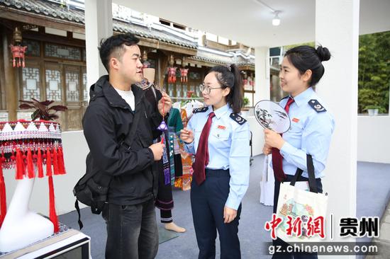 在乡村振兴赋能计划走进贵州毕节七星关暨2024太极古茶文化推广季活动现场，商家向七星关区税务局“春风志愿团队”干部介绍苗绣民族产品。郑婷摄