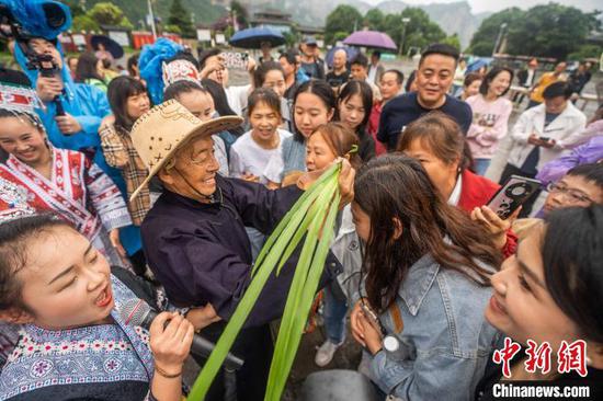6月7日，在贵州省黔西市新仁苗族乡化屋村，村民为游客点雄黄酒。
