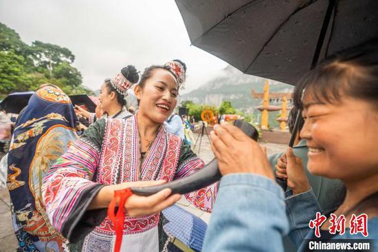 6月7日，在贵州省黔西市新仁苗族乡化屋村，村民为游客敬酒。