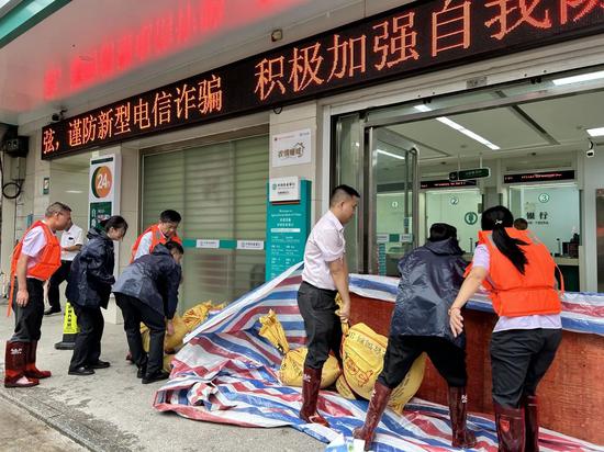 图为农行广西梧州岑溪市支行正在组织地势低洼的南渡支行网点开展防洪应急准备
