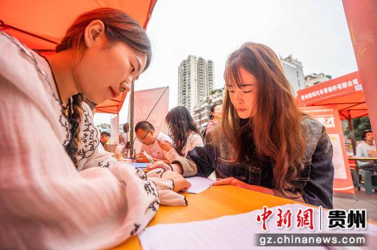 2024年6月19日,市民在贵州省毕节市公园路的街头招聘会现场填写表格信息。 2024年6月19日,市民在贵州省毕节市公园路的街头招聘会现场填写表格信息。