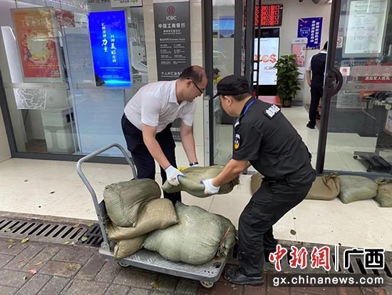 图为工行员工合力搬运沙袋，共同抵御内涝风险，确保营业网点正常运营。