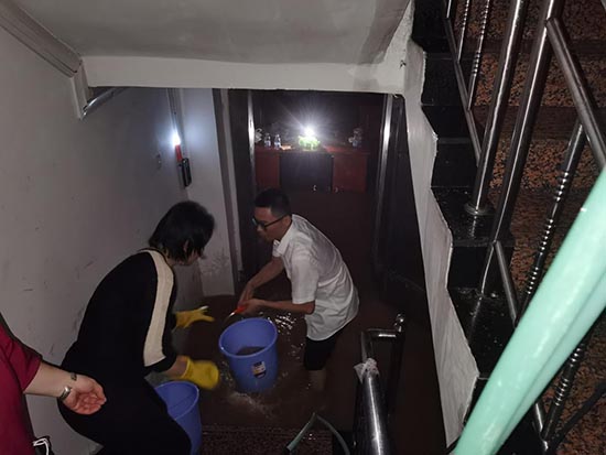 图为员工紧密配合，清除地下业务区积水，全力保障财产安全。