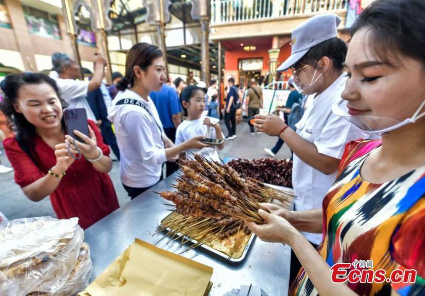 A mutton kebab stall holder serves visitors at the Second Xinjiang Barbecue Festival held at the Grand Bazaar in Urumqi, Northwest China's Xinjiang Uyghur Autonomous Region, June 15, 2024. (Photo: China News Service/Liu Xin)

