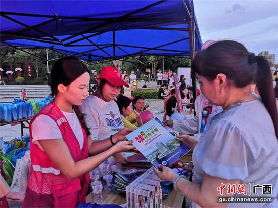 志愿者在向居民发放宣传手册。南宁高新区 供图 志愿者在向居民发放宣传手册。南宁高新区 供图