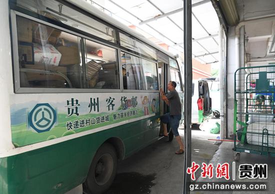 在松桃苗族自治县邮政公司邮件处理中心，司机在搬运货物到车上。