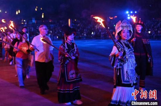 8月2日晚，贵州六盘水海坪彝族风情小镇火把广场的火把节活动吸引游客参加。2024年海坪彝族火把季于7月13日开幕，活动持续至8月11日。本次活动围绕取火、送火的火把节传统文化核心，展现彝族文化的魅力，吸引游客参加。中新社记者 陈楚红 摄