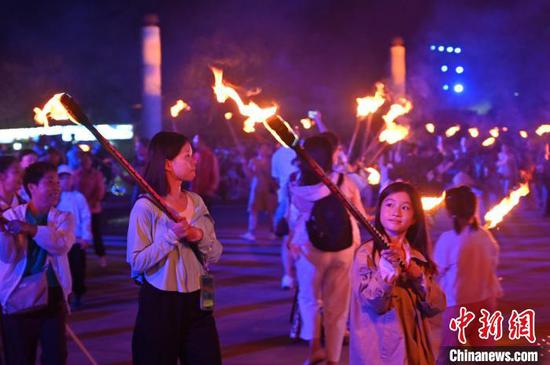 8月2日晚，贵州六盘水海坪彝族风情小镇火把广场的火把节活动吸引游客参加。2024年海坪彝族火把季于7月13日开幕，活动持续至8月11日。本次活动围绕取火、送火的火把节传统文化核心，展现彝族文化的魅力，吸引游客参加。中新社记者 陈楚红 摄