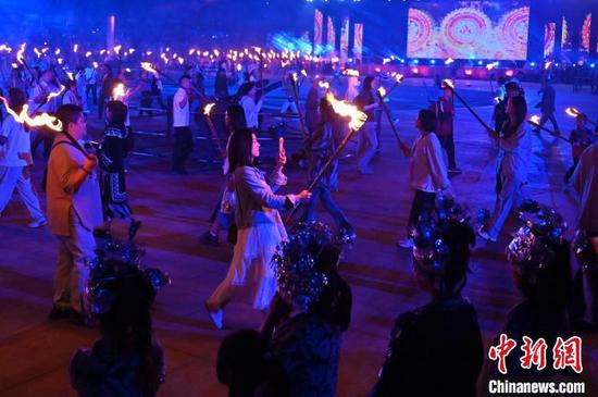 8月2日晚，贵州六盘水海坪彝族风情小镇火把广场的火把节活动吸引游客参加。2024年海坪彝族火把季于7月13日开幕，活动持续至8月11日。本次活动围绕取火、送火的火把节传统文化核心，展现彝族文化的魅力，吸引游客参加。中新社记者 陈楚红 摄