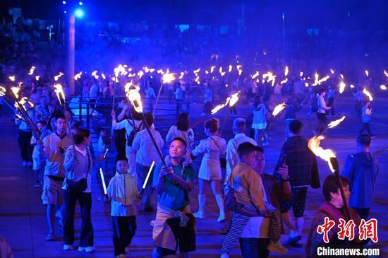 8月2日晚，贵州六盘水海坪彝族风情小镇火把广场的火把节活动吸引游客参加。2024年海坪彝族火把季于7月13日开幕，活动持续至8月11日。本次活动围绕取火、送火的火把节传统文化核心，展现彝族文化的魅力，吸引游客参加。中新社记者 陈楚红 摄