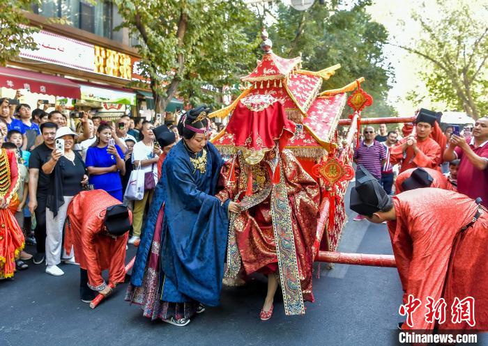 8月9日，新疆烏魯木齊市沙依巴克區(qū)和田二街，明制漢婚娶親巡游中，八抬大轎緩緩落下，“新娘”步出花轎。當(dāng)日，一場傳統(tǒng)婚俗展示巡游活動在此舉行，漢族、維吾爾族、哈薩克族三支送親隊伍，再現(xiàn)了各民族傳統(tǒng)婚俗的熱鬧場景，吸引眾多市民及游客圍觀。中新社記者 劉新 攝