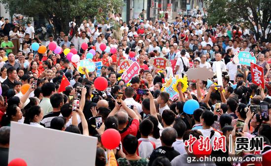 9月11日，在贵州省黔东南苗族侗族自治州施秉县城，家乡人民举着旗帜、横幅和各种宣传标语，热烈欢迎巴黎残奥冠军杨洪载誉回乡。向天祥 摄