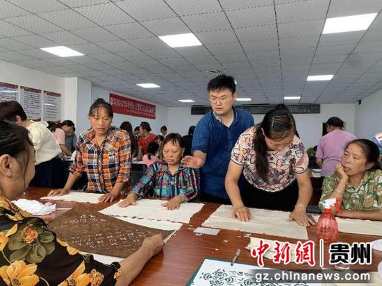 韦祥龙指导绣娘进行蓝染图案定位 。岑家乡摄