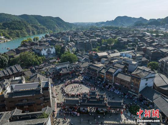 10月4日，国庆假期，贵州省黔东南苗族侗族自治州凯里市下司古镇秋景迷人。吸引了不少游客驻足游玩。图为航拍游客在下司古镇观看民俗表演。（无人机照片）