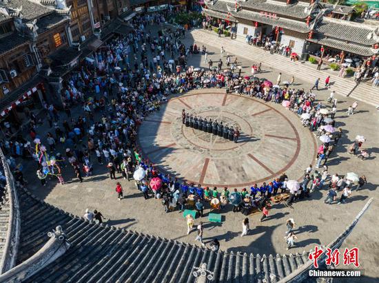 10月4日，国庆假期，贵州省黔东南苗族侗族自治州凯里市下司古镇秋景迷人。吸引了不少游客驻足游玩。图为航拍游客在下司古镇观看民俗表演。（无人机照片）