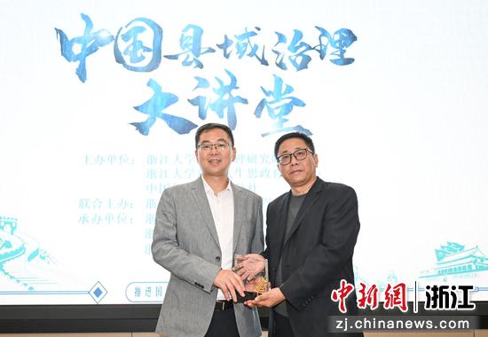 图为:浙江大学社会治理研究院副院长、浙江大学马克思主义学院副院长陈宝胜(右)为柯桥区委书记陈豪颁发纪念品。中新社记者 王刚 摄