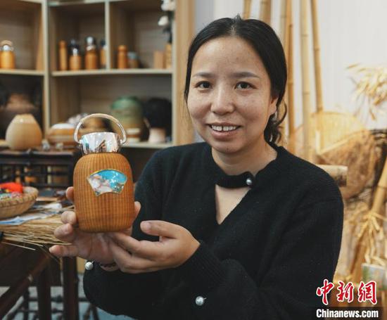图为杨杜娟展示镶嵌了掐丝珐琅画的竹编保温杯。周燕玲 摄 图为杨杜娟展示镶嵌了掐丝珐琅画的竹编保温杯。周燕玲 摄