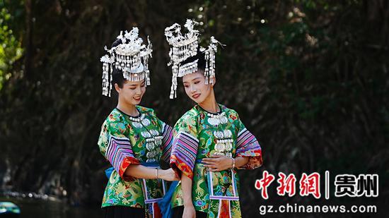 2024年10月26日，两名身着水族盛装的女孩在河边整理服装。韦贵金 摄