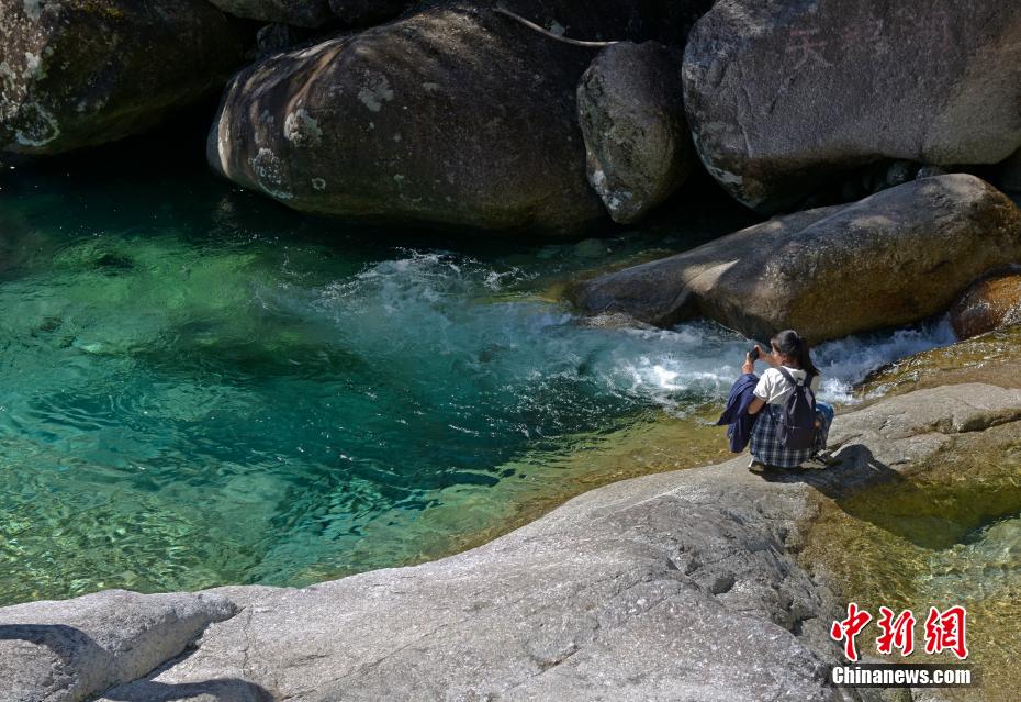 广西第一高峰猫儿山地跨兴安、资源、龙胜3县，海拔2141.5米，因形体似猫而得名，素有“华南之巅”美誉。深秋时节，猫儿山的景色吸引了许多游客前往观景。图为游客在猫儿山山间的水潭拍照留念。滕忠 摄