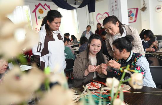 11月14日,在松桃苗族自治县蓼皋街道团山社区,传统手艺人黄松琴(右一)在教人们编织手工产品。谢慧芳摄 11月14日,在松桃苗族自治县蓼皋街道团山社区,传统手艺人黄松琴(右一)在教人们编织手工产品。谢慧芳摄