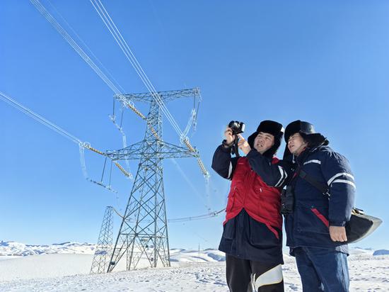 11月24日,新疆送变电公司员工杨林、叶俊涛在750千伏伊库一线176号塔开展雪后特巡。巴依尔 摄 11月24日,新疆送变电公司员工杨林、叶俊涛在750千伏伊库一线176号塔开展雪后特巡。巴依尔 摄