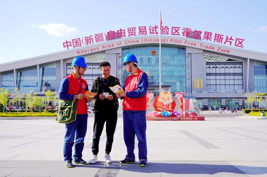 國家電網(wǎng)新疆電力天山雪蓮（伊犁伊河）共產(chǎn)黨員服務(wù)隊(duì)隊(duì)員在霍爾果斯“自貿(mào)區(qū)”聯(lián)檢大樓向過往游客介紹安全用電知識(shí)。白玉 攝