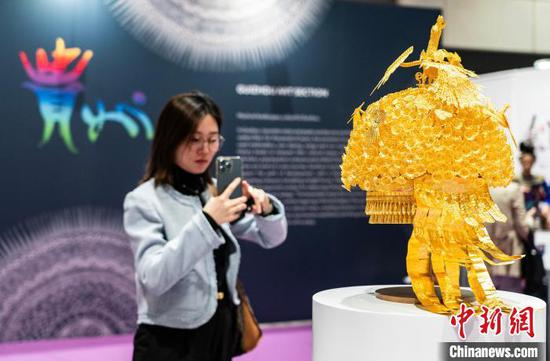 图为一位女士拍摄“金凤朝阳苗冠”展品。　中新网记者 侯宇 摄