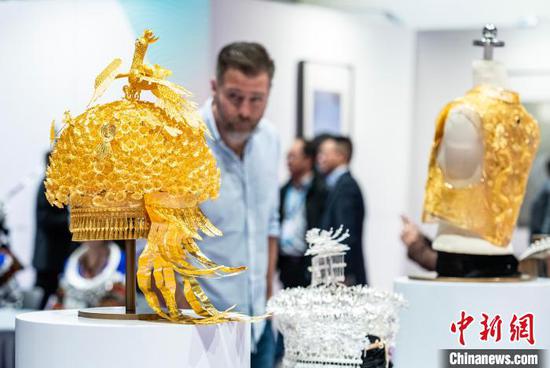 图为贵州省展区内的“金凤朝阳苗冠”展品(左)等吸引参观者目光。中新网记者侯宇摄