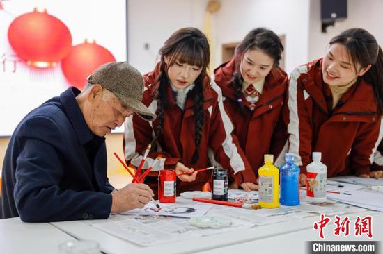 图为民间艺人在幼儿园教老师们画龙灯会人物脸谱。磨桂宾 摄