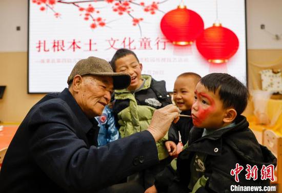 图为民间艺人给小朋友画龙灯会人物脸谱。磨桂宾 摄
