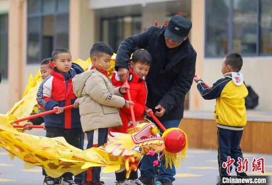 图为民间艺人在幼儿园教小朋友舞龙。磨桂宾 摄