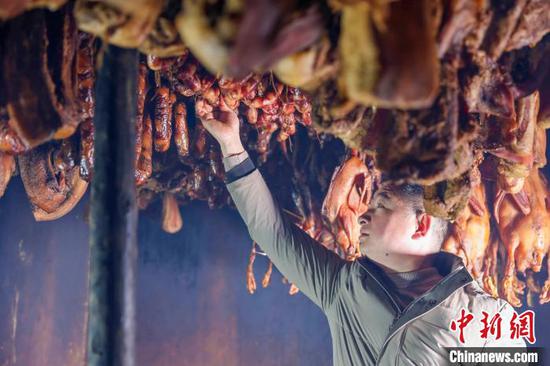 图为贵州施秉云台村一农家乐业主在查看熏制腊肉、香肠的情况。磨桂宾 摄