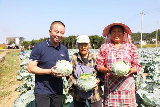资料图：贵州合力超市集团董事长李德祥（左）与乌当区大坝村农户采收莲花白