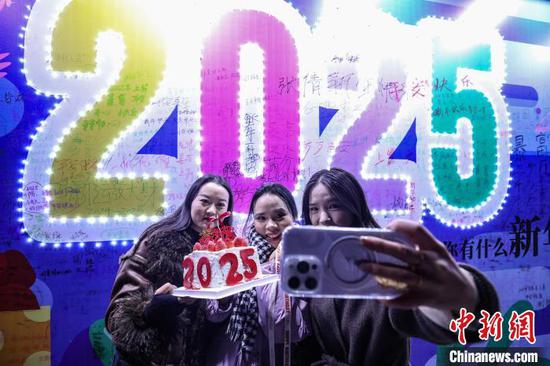 12月31日晚，2025贵阳路边音乐会跨年嘉年华在贵州省贵阳市观山湖区举行，吸引众多游客与市民前来参与，迎接2025年的到来。图为市民手拿2025年字样蛋糕自拍。中新社记者 瞿宏伦 摄